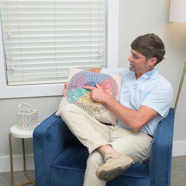 Man sitting in a chair pointing to a pillow